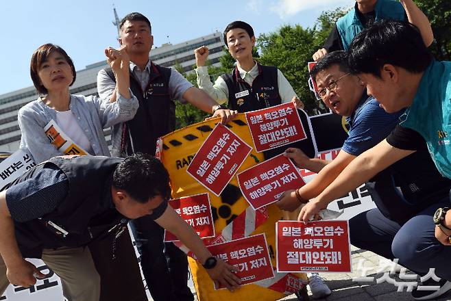지난달 22일 서울 용산구 전쟁기념관 앞에서 열린 '일본 핵 오염수 해양투기 저지 투쟁 선포 민주노총 전국동시다발 기자회견' 참석자들이 드럼통에 스티커를 부착하는 상징의식을 하고 있다. 황진환 기자