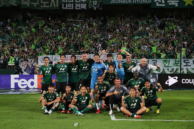 전북 현대 선수들이 6일 전주월드컵경기장에서 열린 2023 K리그1 인천 유나이티드와 경기가 끝난 뒤 팬들과 기념사진을 찍고 있다. 선수들 뒤로 걸린 팬 걸개에는 “잼버리도 망치고 전북도 망치고”라는 글이 적혀있다. 한국프로축구연맹 제공