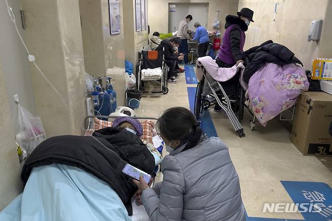 [베이징=AP/뉴시스] 3일 중국 베이징 시내 병원 응급병동 복도에 링거를 꽂은 노인들이 보호자의 보살핌을 받으며 누워 있다. 유럽연합(EU)은 코로나19 방역 완화로 확진자가 급증한 중국을 돕기 위해 무료로 백신을 제공하기로 했다. 2023.01.03