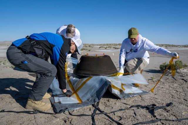 24일 미국 항공우주국(NASA·나사) 직원들이 미 유타주(州) 사막의 국방부 시험·훈련장에 떨어진 소행성 토양 샘플 캡슐을 회수하고 있다. 2016년 9월 발사된 소행성 탐사선 '오시리스-렉스(OSIRIS-Rex)'가 소행성 '베누(Bennu)'에서 채취한 표면 토양 샘플이 담겨 있다. AP 연합뉴스