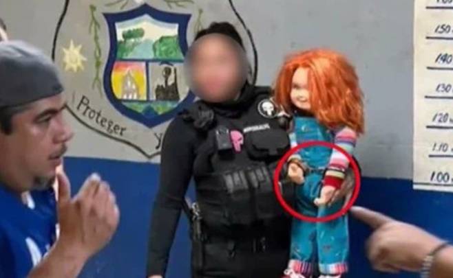 사진=여경이 수갑을 찬 인형을 안고 머그샷을 찍고 있다.