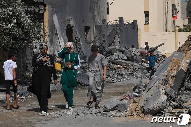 25일(현지시간) 가자지구 남부의 라파 난민 캠프에 이스라엘의 공습이 이어진 후 팔레스타인인들이 건물 잔해를 옆을 지나고 있다. 2023.10.26 ⓒ AFP=뉴스1 ⓒ News1 정지윤 기자