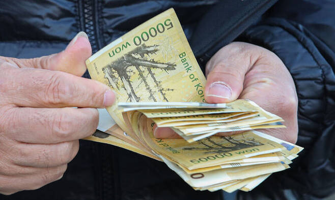 서울 시내의 한 은행 ATM에서 시민이 현금 5만원권을 세고 있다. 뉴시스