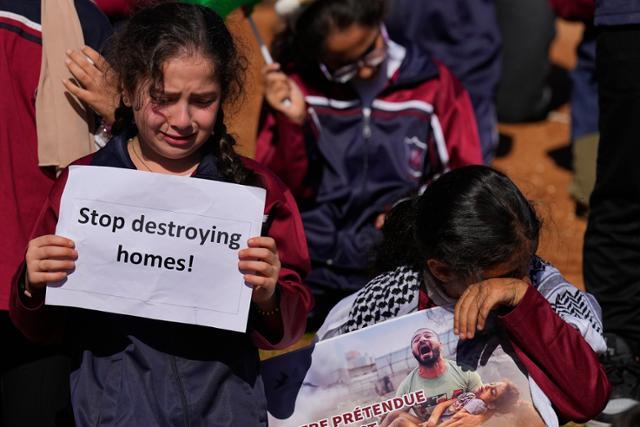 21일 레바논 베이루트에 있는 유엔 서아시아경제사회위원회(ESCWA) 본부 앞에서 열린 이스라엘 공습 반대 시위에 참석한 소녀들이 손팻말을 든 채 눈물을 흘리고 있다. 베이루트=AP 뉴시스