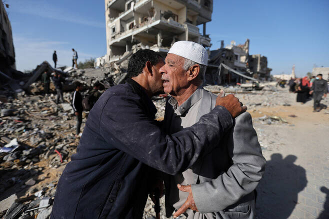 3)하마스와 이스라엘의 합의에 따라 교전이 잠시 중단된 11월24일 팔레스타인 땅 가자지구 남부 칸유니스의 무너진 건물 앞에서 주민들이 얼싸안으며 인사를 나누고 있다. REUTERS 연합뉴스
