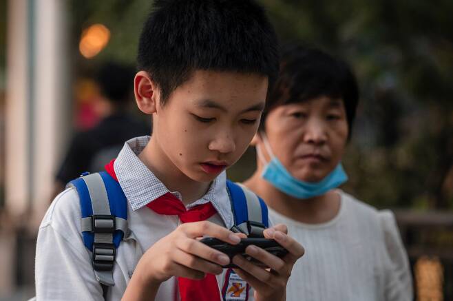 지난 22일 중국 상하이의 한 거리에서 학생이 휴대전화를 들여다보고 있다. 중국 정부는 청소년의 인터넷 게임, 라이브 방송 사용에 대한 규제를 강화하고 있다./EPA 연합뉴스