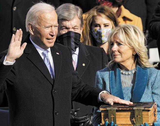 128년 된 家寶성경에 손얹고 취임 선서 - 조 바이든(왼쪽) 미 대통령이 20일(현지 시각) 워싱턴DC의 의회 의사당 앞에서 열린 취임식에서 대통령 부인 질 바이든(오른쪽) 여사가 들고 있는 성경에 손을 얹고 취임 선서를 하고 있다. 이 성경은 1893년부터 바이든 집안에서 전해져 내려온 것이다. 바이든은 이날 취임사에서“오늘 내 영혼은 오직‘미국을 하나로 모으는 것’에 달려 있다”고 했다. /AFP 연합뉴스