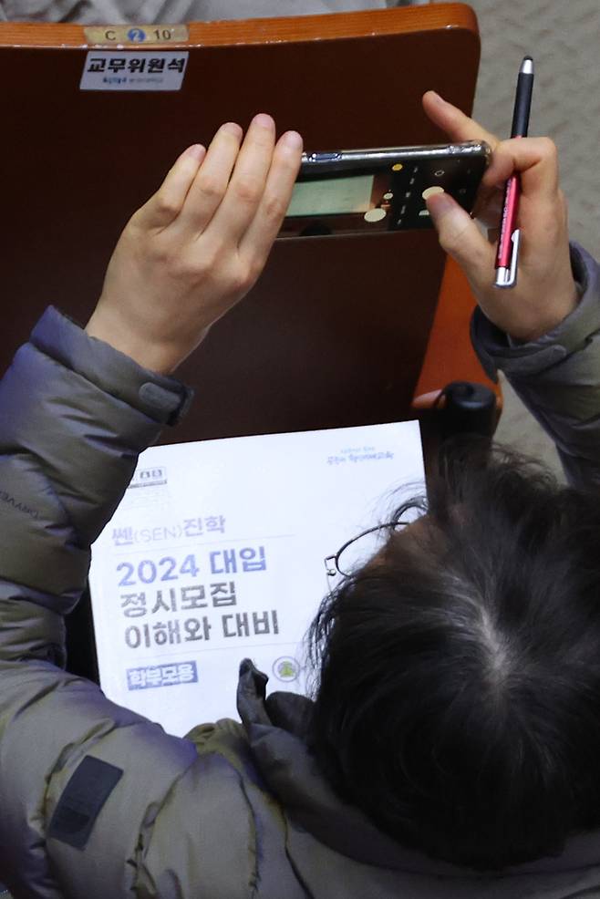 지난달 숭실대에서 열린 서울시교육청 주최 2024 대입 정시모집 설명회에서 수험생과 학부모들이 지원전략 설명을 들으며 스마트폰을 이용해 강의자료를 기록하고 있다.