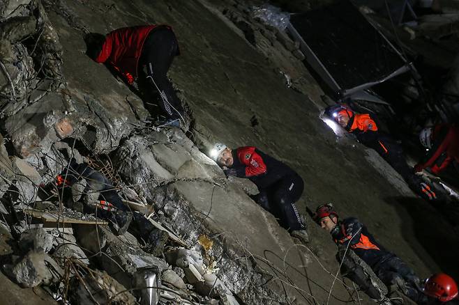 남부 이스켄데룬 지역에서 구조대원들이 건물 콘크리트 잔해에 귀를 바짝 대고 실종자들이 내는 생존 신호를 잡아내려는 모습. /EPA 연합뉴스