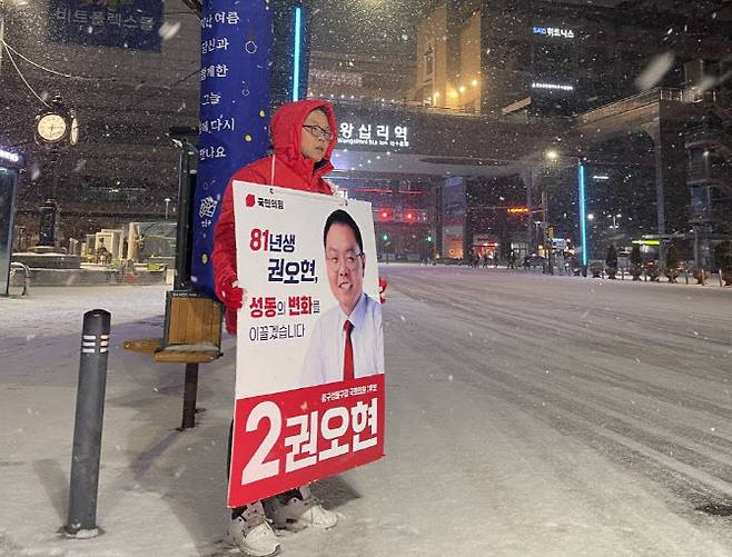 굵은 눈발이 휘날리던 지난 9일 성동구 왕십리역 앞에서 권오현 변호사가 팻말을 들고 있다. (사진=본인 제공)