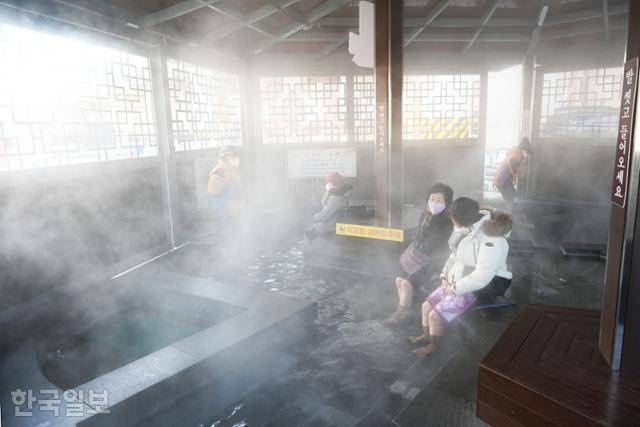온양온천역 족욕체험장에서 주민과 관광객이 뜨끈한 온천수에 발을 담근 채 휴식하고 있다.