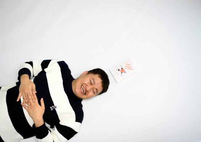지난달 23일 서울 중구 문화일보에서 만난 김동식 작가가 바닥에 누워 환하게 웃고 있다. 머리 위엔 데뷔 후 처음 발표한 에세이가 놓여 있다. 윤성호 기자