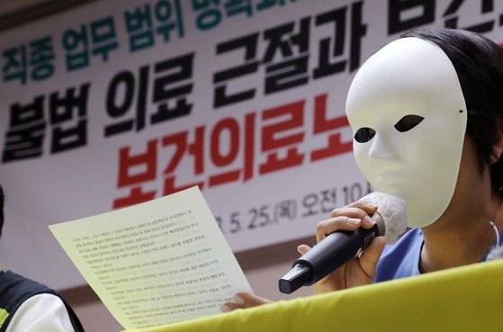 가면을 쓴 의료기관 소속 PA 간호사가 지난해 5월 25일 서울 영등포구 전국보건의료산업노조 사무실에서 열린 '보건의료 근본 과제 해결 촉구' 기자회견에서 직종 업무 범위 명확화, 무면허 불법 의료 근절, 간호사 처우개선 등을 촉구하고 있다. 뉴스1