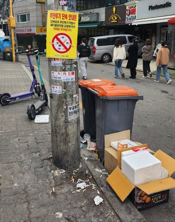 서울 마포구 홍대입구역 근처 골목길에 설치된 "담배꽁초 무단투기 적발시 과태료 부과됩니다"라는 안내판 아래로 담배꽁초가 한가득 쌓여있다. 김서원 기자