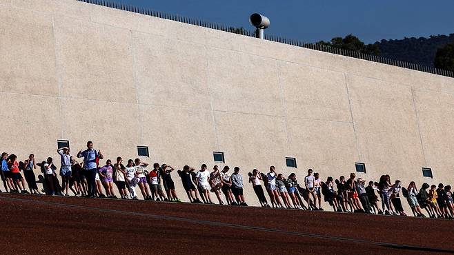 7일 오스트레일리아 캔버라 국회의사당에서 열린 팜 민 친 베트남 총리의 공식 환영식에 참가한 학생들이 행사 시작을 기다리며 벽에 기대어 쉬고 있습니다./AFP 연합뉴스