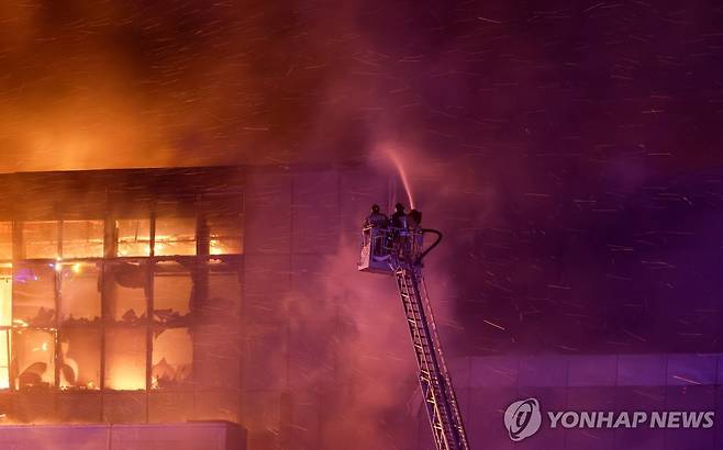 진화 중인 소방대원 (크라스노고르스크 로이터=연합뉴스) 22일(현지시간) 무차별 총격 사건이 벌어진 러시아 모스크바 외곽 대형 콘서트장에서 소방대원이 진화를 하고 있다. 2023.3.23