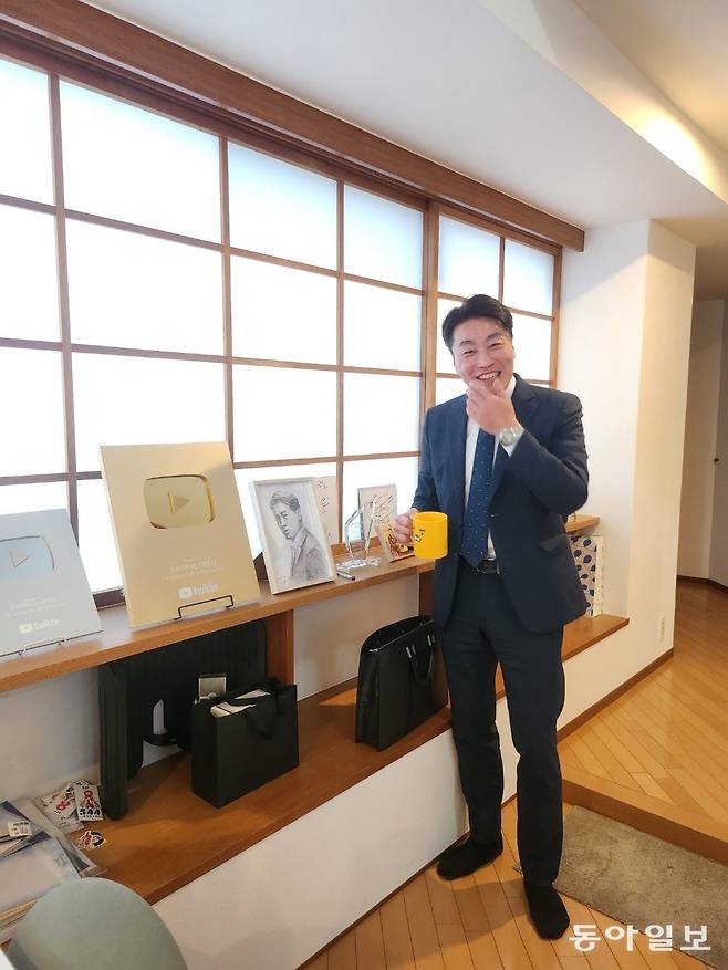 마츠다 씨가 유튜브 실버버튼(10만 돌파), 골드버튼(100만 돌파) 버튼 앞에서 커피잔을 들고 있다. 카카오톡의 캐릭터 ‘라이언’이 그려져 있는 귀여운 잔이었다. 오사카=황인찬 기자 hic@donga.com