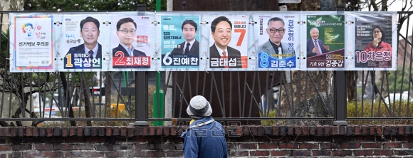 누구를 찍어야 하나 - 4·10 총선의 공식 선거운동이 시작된 28일 오전 서울 종로구 대학로 인근을 지나던 한 시민이 후보들의 사진과 이름이 붙은 선거 벽보를 바라보고 있다. 도준석 전문기자