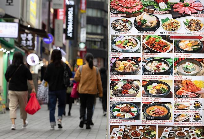 서울 중구 명동거리 음식점 메뉴판 앞으로 외국인 관광객들이 지나가고 있다. /뉴스1