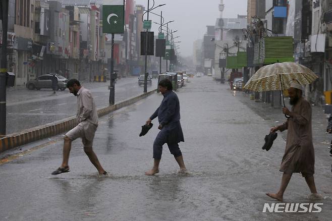 [AP/뉴시스] 15일 파키스탄 폐샤와르 주민들이 폭우 속에 길을 건너고 있다