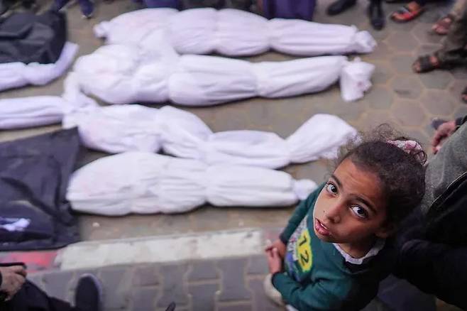 지난 3월 가자지구 데이르알발라에 위치한 알아크사 병원에서 한 팔레스타인 소녀가 전날 폭격으로 숨진 시신 앞에 서 있다. AFP연합뉴스