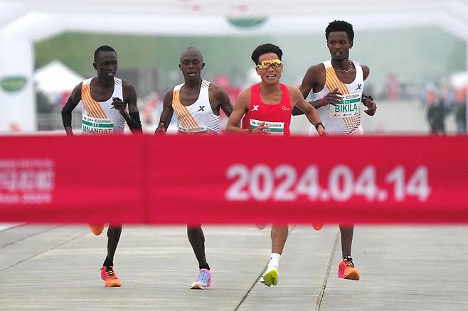 14일(현지시각) 중국 베이징에서 열린 하프 마라톤 대회에서 붉은옷을 입은 중국의 허제 선수가 앞서 들어오고, 잇달아 아프리카 선수 3명이 1초 차이로 공동 2등을 했다. /로이터 연합뉴스