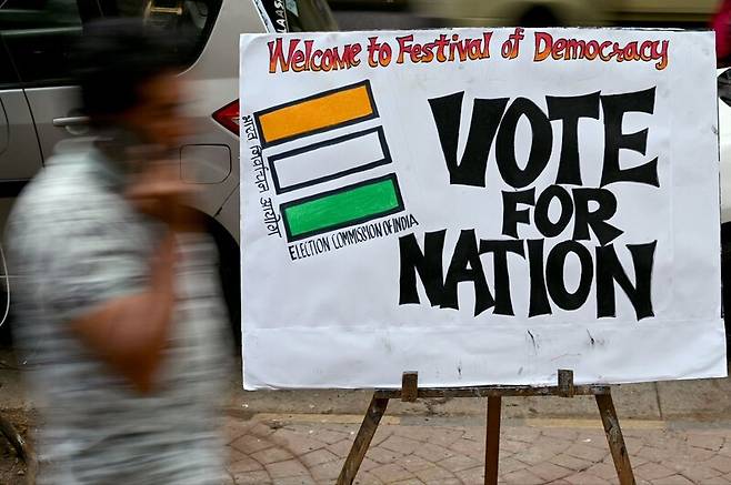지난 17일 인도 뭄바이에서 한 행인이 인도 총선 투표를 독려하는 포스터 앞을 지나가고 있다. AFP 연합뉴스