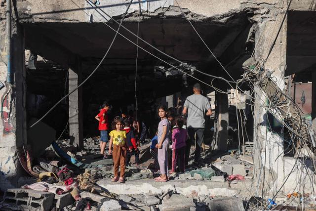 팔레스타인 아이들이 17일 가자지구 남부 도시 라파에서 전날 이스라엘군 공습으로 무너져 내린 건물 잔해를 탐색하고 있다. 라파=AFP 연합뉴스
