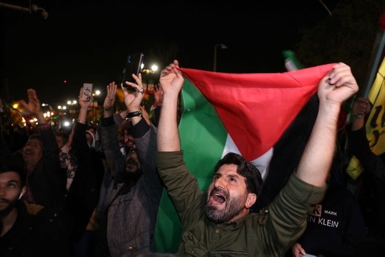 이란이 이스라엘에 드론과 미사일 공격을 가한 후 14일 이란 테헤란 주재 영국 대사관 앞에 모인 시위대들이 이란 국기를 흔들고 있다. 로이터=연합뉴스