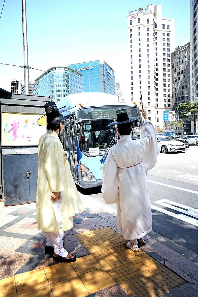 지난 13일 서울 중구의 한 버스 정류장에서 송민근(오른쪽)씨가 손에 쥐고 있던 전통 부채를 들어 올려서 버스 탑승 의사를 표현하고 있다. /주민욱 영상미디어 기자