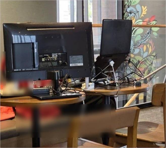 한 프랜차이즈 카페에서 손님이 좌석에 모니터를 설치해 작업을 하고 있는 모습을 촬영한 사진이 화제가 되고 있다. (사진=온라인 커뮤니티 갈무리)