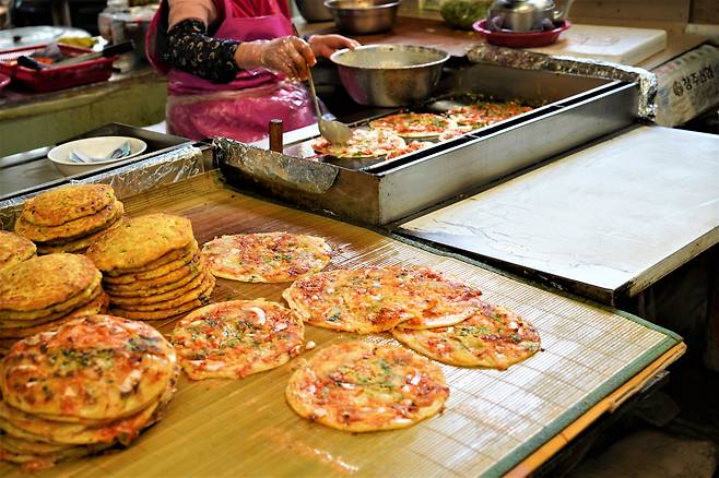 Kimchi pancakes are grilled at Yukgeori Market in Cheongju, North Chungcheong Province, April 11. (Lee Si-jin/The Korea Herald)