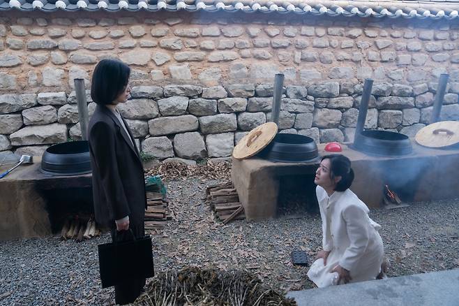 Choi Hye-jeong kneels down to ask Moon Dong-eun's forgiveness for her past deeds in "The Glory." (Netflix)