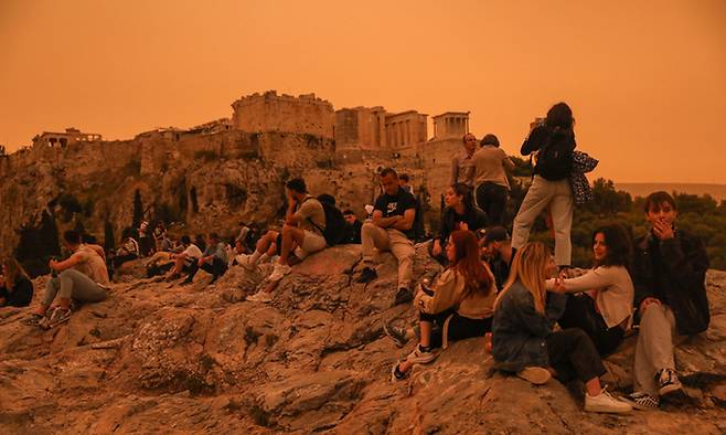 아프리카 북부 사하라사막의 모래먼지가 그리스를 강타한 가운데 23일(현지시간) 관광객들이 주황색 먼지로 가득 찬 대기 속 그리스 아테네의 아크로폴리스를 바라보고 있다. 아테네=EPA연합뉴스