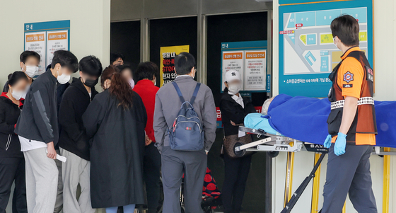 Patients and their families wait in line in front of an emergency center at a university hospital in Seoul on Thursday. [NEWS1]