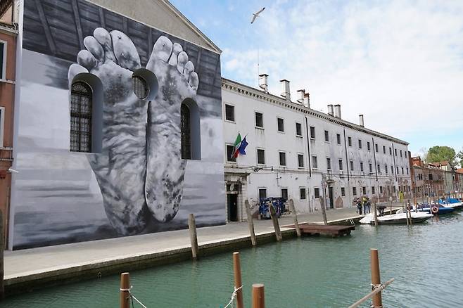 이탈리아 베네치아의 한 교회 외벽에 상처투성이 맨발을 묘사한 이탈리아 예술가 마우리치오 카텔란의 작품 ‘아버지’가 전시되고 있다. 오는 11월 24일까지 열리는 제60회 베네치아비엔날레 교황청 파빌리온 전시 작품이다.  <EPA연합뉴스>