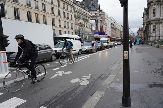 파리시청 앞 도로에서 자전거를 탄 시민들이 꽉 막힌 차량 행렬을 지나고 있다. 파리시는 친환경등급제 시행과 함께 도로를 줄이는 대신 자전거도로를 넓히는 등 대체 교통수단을 확대하고 있다. 중앙포토