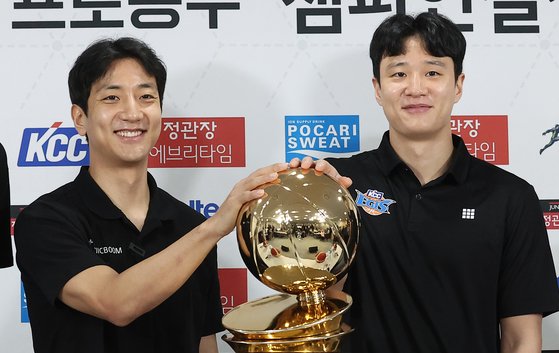 우승 트로피를 만지며 웃는 KT 허훈(왼쪽)과 KCC 허웅. 뉴스1