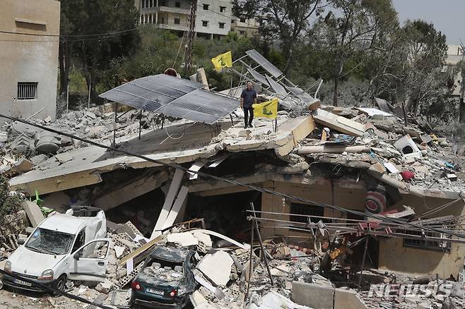 [하난(레바논)=AP/뉴시스]레바논 남부 하난 마을에서 25일 한 남성이 이스라엘군의 공습으로 파괴된 집 위에 서 있다. 레바논의 무장단체 헤즈볼라가 국경 분쟁지역의 이스라엘군 호송차량을 향해 대전차 미사일과 포탄을 발사, 이스라엘 민간인 1명이 사망했다고 헤즈볼라와 이스라엘군이 26일 밝혔다. 2024.04.26.