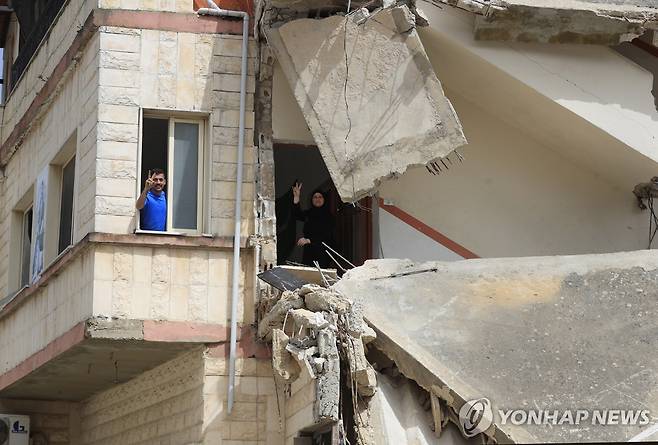 이스라엘군의 공습으로 파괴된 집에서 'V'자를 그려보이는 레바논 주민들 [AP 연합뉴스자료사진. 재판매 및 DB 금지]