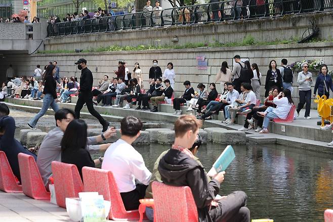 서울지역 낮 최고기온이 25도까지 오르며 초여름 날씨를 보인 지난 18일 오후 서울 중구 청계천을 찾은 시민과 관광객이 물가에 앉아 더위를 식히고 있다./뉴스1