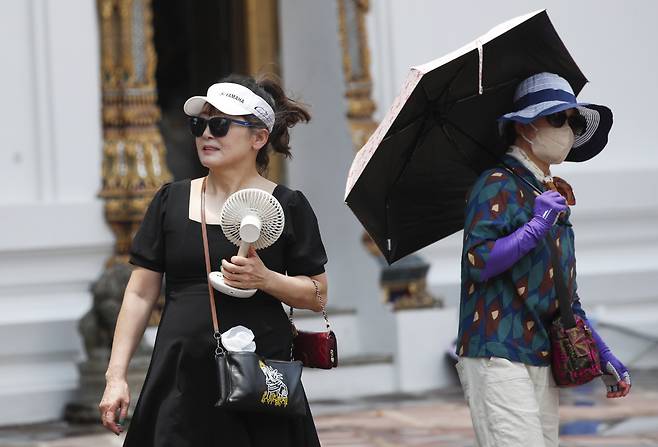 26일 태국 방콕에서 외국인 관광객들이 더운 날씨에 햇빛을 가리고 있다. 태국 기상청은 기온이 섭씨 43도까지 오를 수 있는 날씨가 계속됨에 따라 장기간의 야외 활동을 피하라고 권고했다. [EPA]