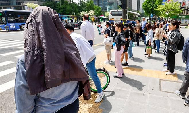 초여름 날씨를 보인 26일 서울 종로구 광화문네거리에서 한 시민이 옷으로 머리를 가린 채 신호를 기다리고 있다. 뉴시스