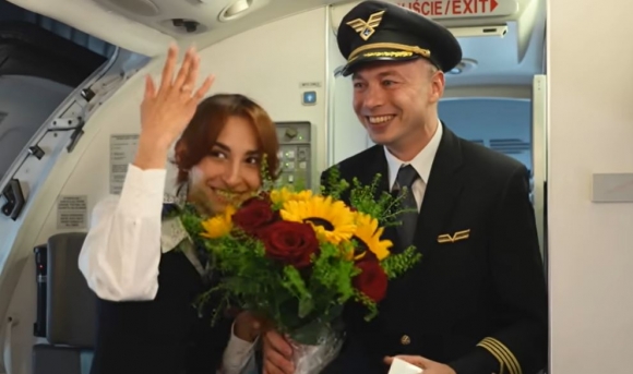 LOT 폴란드 항공 조종사 콘라드 한크(오른쪽)에게 청혼받은 연인이자 승무원인 파울라가 한크로부터 받은 청혼 반지를 낀 손을 승객들에게 보여주고 있다. LOT 폴란드 항공 유튜브 캡처