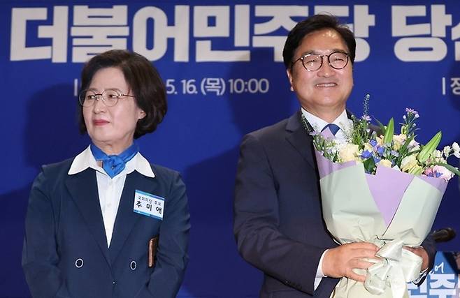 더불어민주당의 국회의장 후보로 선출된 우원식 의원(사진 오른쪽)이 16일 오전 서울 여의도 국회 의원회관에서 열린 제22대 전반기 국회의장단 후보 선출을 위한 당선자 총회에서 꽃다발을 받고서 환하게 웃고 있다. 연합뉴스