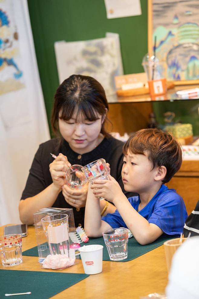 지난 18일 제주 서귀포에서 열린 ‘신효마을 공예축제’ 참가자들이 민화공방 ‘제주그림’에서 유리컵에 귤꽃 그리기 체험을 하고 있다. 이수현 제공