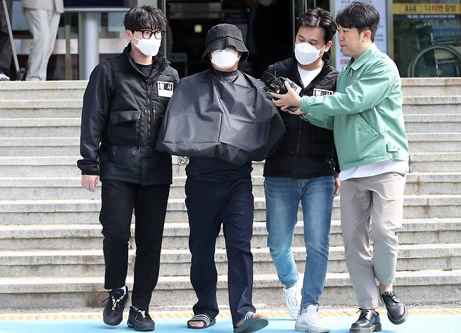 해당 사진은 특정범죄가중처벌법(특가법)상 보복살인 혐의를 받는 50대 유튜버 A씨가 지난 16일 오전 부산 연제구 연제경찰서에서 검찰로 송치되는 모습. A씨의 얼굴과 수갑찬 손은 인권 보호를 위해 가려졌다. /뉴스1