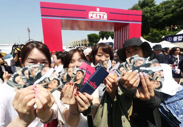 일본에서 온 BTS 팬(아미)들이 13일 서울 송파구 잠실종합운동장 일대에서 열린 ‘2024 페스타’에서 기념품을 들어 보이고 있다. 이날 공식 오픈 시간은 오전 11시였지만, 팬들은 새벽부터 줄을 서서 기다리며 BTS에 대한 애정을 드러냈다. 연합뉴스