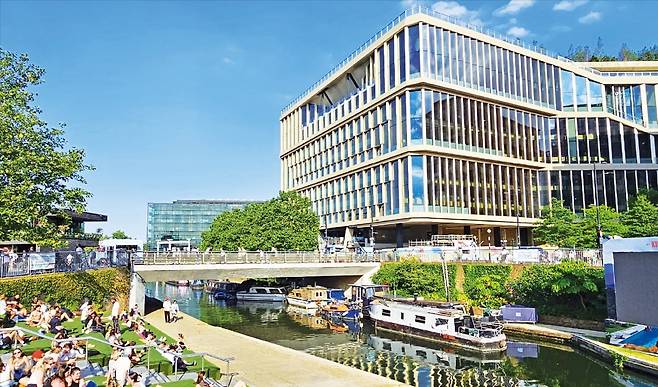 < 대학생·IT직원·주민들로 ‘북적북적’ > 영국 런던 시민들이 지난달 25일 킹스크로스 내 공공문화공간인 콜드롭스야드스텝에서 여가를 즐기고 있다. 이곳은 공연·문화 이벤트가 열리는 그래너리스퀘어 등 다양한 휴식 공간이 있어 종일 인파로 북적인다. 오른쪽은 연내 완공을 앞둔 300m 길이의 구글 런던 헤드쿼터 북측 부분. /런던=이유정 기자