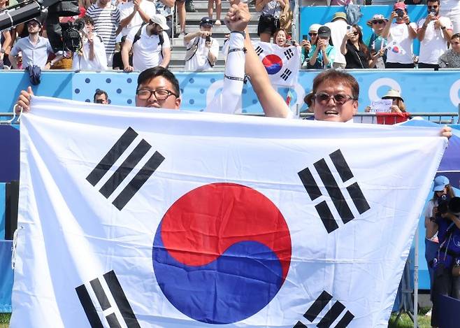 4일(현지시간) 프랑스 파리 레쟁발리드에서 열린 2024 파리올림픽 양궁 남자 개인전 결승에서 승리한 김우진 선수가 박성수 감독과 태극기를 들고 관중에게 인사하고 있다. 연합뉴스 제공